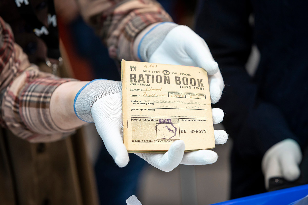Member of staff wearing white gloves holding a ration book.