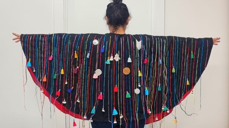 Model wearing a cape that is part of the Sew What exhibition